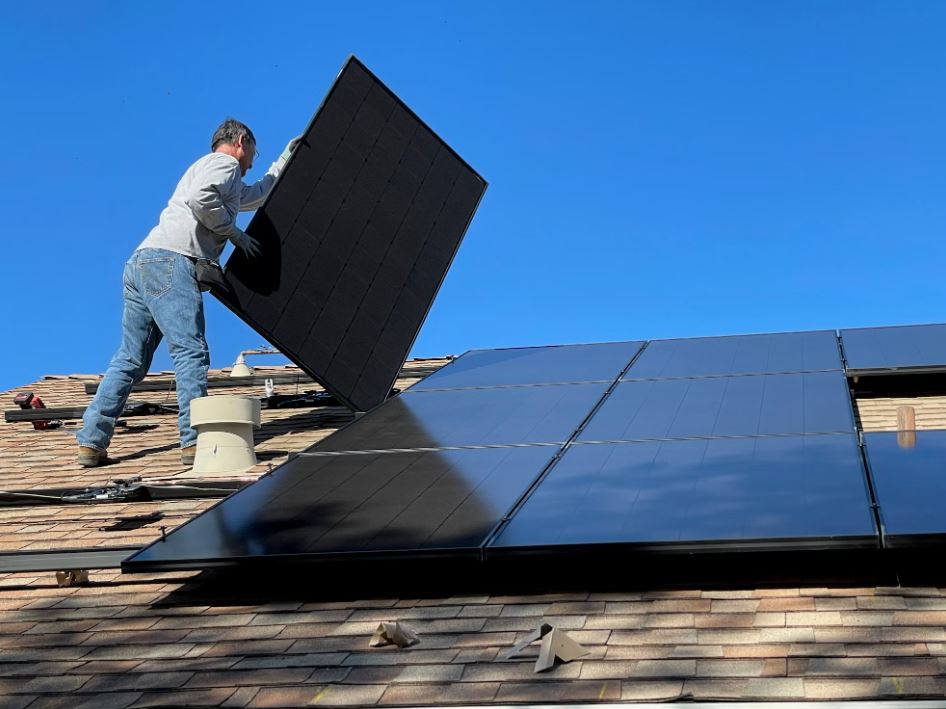 homme en train d'installer panneau solaire avec batterie de stockage